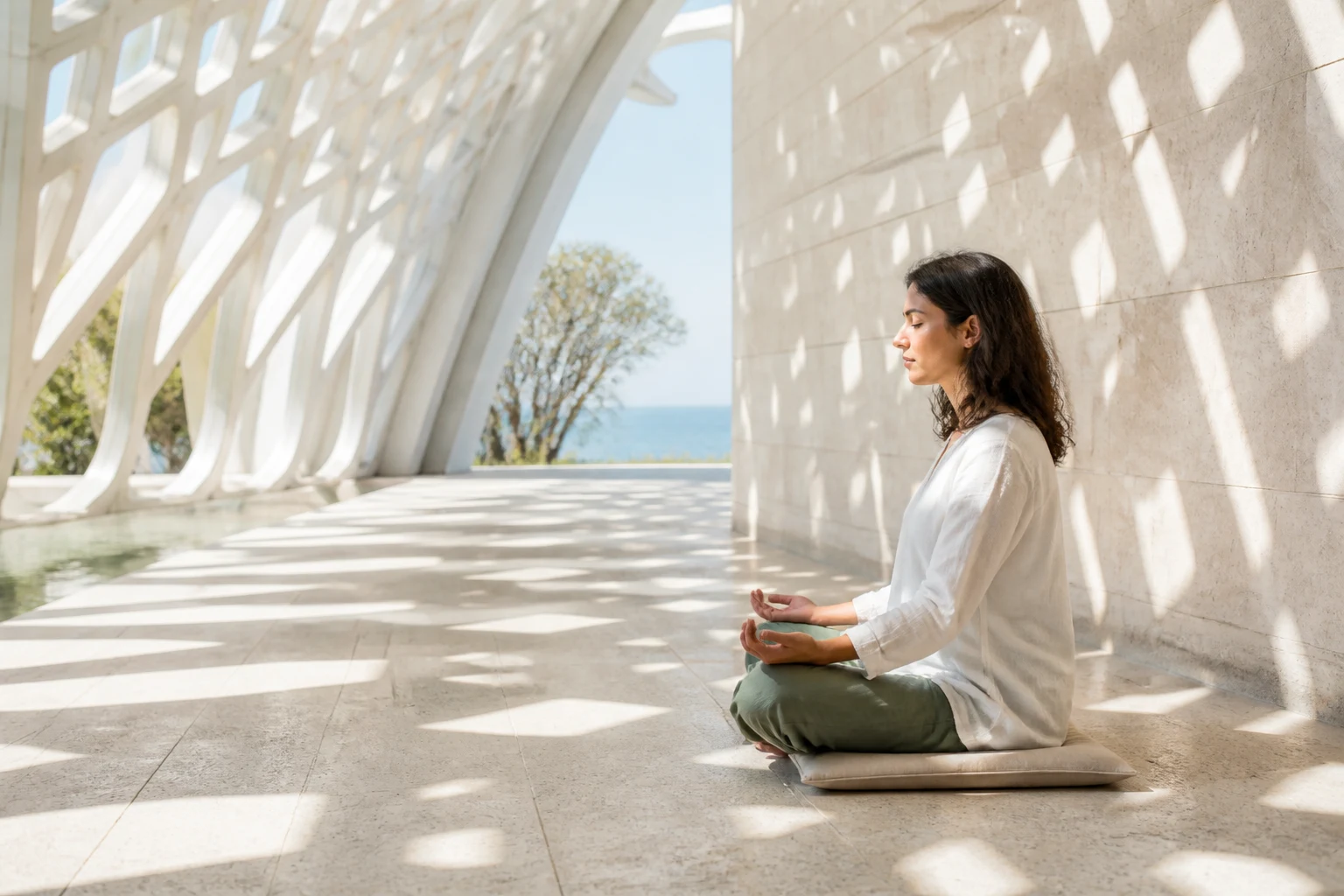 Mujer meditando en un pabellón geométrico luminoso junto al mar