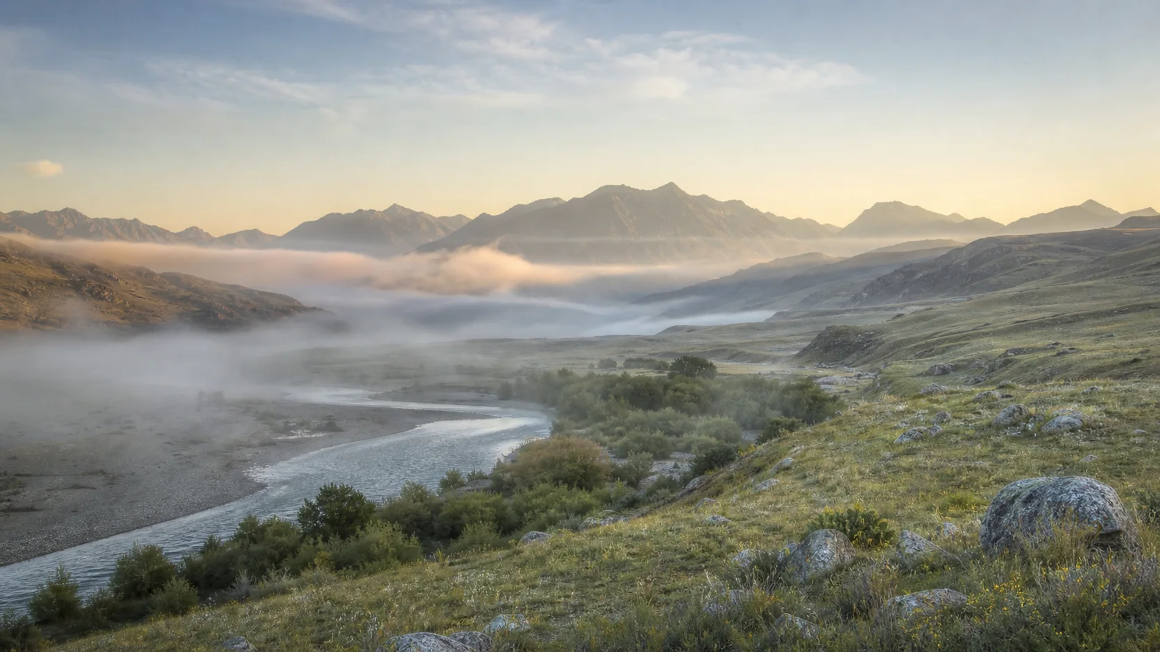 Valle montañoso luminoso con río y niebla suave, una imagen natural y contemplativa