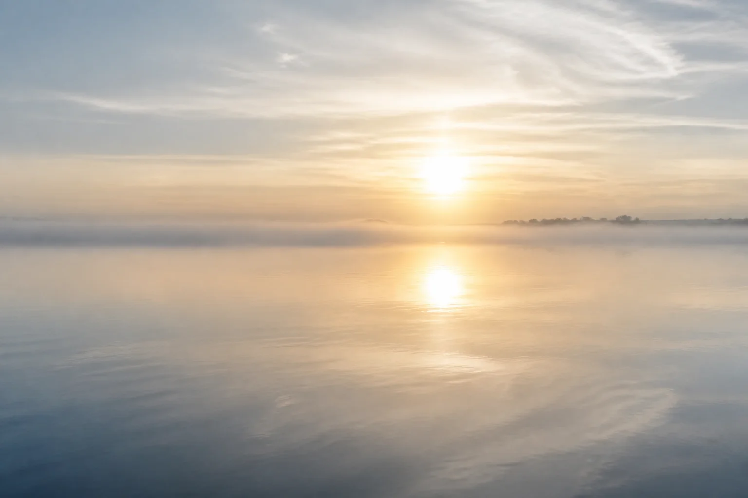 Horizonte luminoso sobre agua tranquila y niebla suave como metáfora de transición